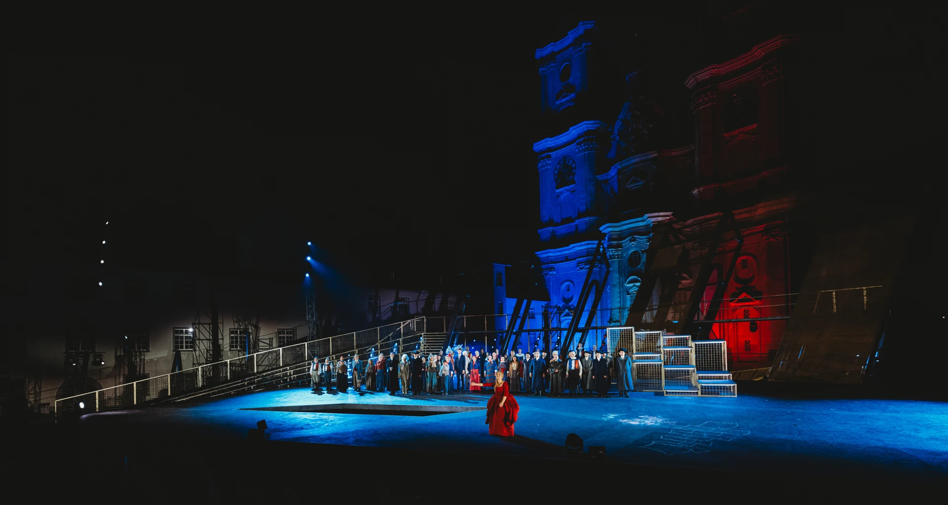 Ensemble von Andrea Chénier vor der blau und rot beleuchteten Kathedrale von St. Gallen