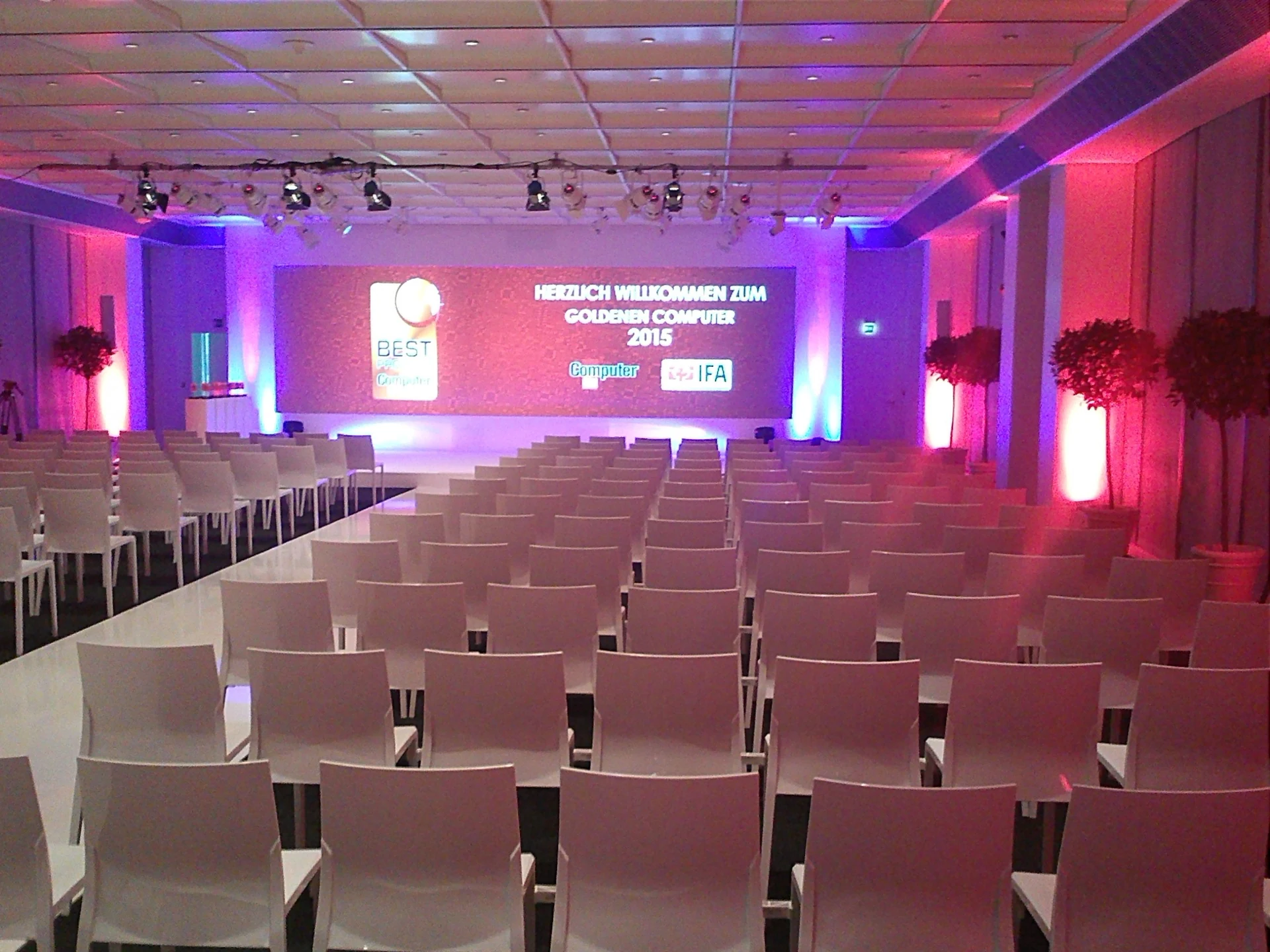 Konferenzsaal mit weißen Stühlen und violetter Architekturbeleuchtung